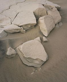 some rocks are laying on the sand by the water's edge and there is no image here to provide a caption for