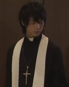 a young man wearing a priest's outfit and holding a cross