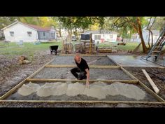 a man kneeling down next to a pile of cement on top of a dirt field