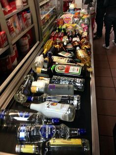 a display case filled with lots of different types of drinks and condiments for sale