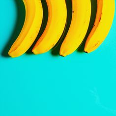 four bananas are lined up against a blue background