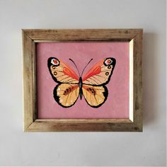 an orange butterfly painted on pink paper in a wooden frame