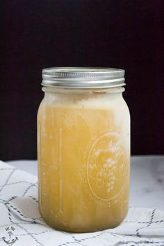 a glass jar filled with liquid sitting on top of a white cloth covered tablecloth