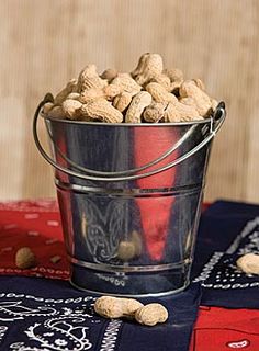 a bucket filled with peanuts sitting on top of a table next to a red and white cloth