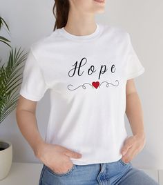 "This \"HOPE\" T-shirt is a classic unisex jersey short-sleeve tee. It reminds us to have Hope in all things. It is made of soft cotton and quality print. These t-shirts have ribbed knit collars to bolster shaping.  .: 100% Airlume combed and ringspun cotton  .: Tear away label Thank you for visiting the - \"Think Happy With Tammy Shop\" Here is a link to another product of ours in the Forgiveness theme that you might like.  https://www.etsy.com/listing/1486791636/christian-forgiveness-mugs-coff Gift Crew Neck T-shirt With Custom Print, Letter Print Crew Neck Tops For Gifts, Pre-shrunk White Print Crew Neck T-shirt, Graphic Tee Crew Neck T-shirt As Gift, White Letter Print Top As Gift, Custom Print Crew Neck Top As Gift, Custom Print Crew Neck Top For Gift, White Letter Print Top As A Gift, Short Sleeve T-shirt With Letter Print