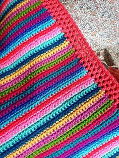 a crocheted blanket is laying on the ground