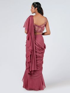 This is a two-piece mauve pre drape ruffle saree set from the Suruchi Parakh collection. The mauve ruffle saree in soft organza is paired with a crop top blouse. The georgette crepe blouse has padding and a back hook opening. There is beautiful floral print work all over the blouse. The hand-embroidered blouse enhances the pre draped saree in mauve color. Festive Draped Choli With Ruffles, Festive Draped Ruffle Choli, Festive Draped Ruffled Choli, Festive Draped Ruffles Choli, Elegant Draped Choli With Ruffles, Fitted Ruffled Saree, Draped Ruffle Sets For Evening, Draped Ruffles Sets For Evening, Draped Ruffles Evening Set