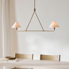 a light fixture hanging over a dining room table with two lamps on top of it