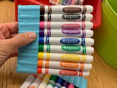 a hand holding a stack of crayons on top of a wooden table