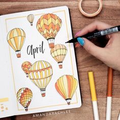 a person is writing on a notebook with hot air balloons