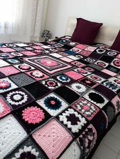 a bed with a crocheted bedspread and pillows on top of it