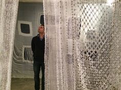 a man is standing in front of some white curtained walls and looking up at the ceiling