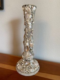 there is a vase made out of seashells and pearls on the table top