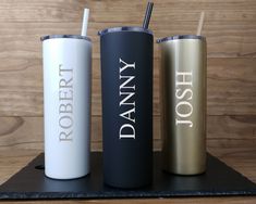 three personalized tumblers sitting on top of a wooden table next to each other