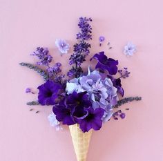 purple flowers in an ice cream cone on a pink background with blue and white flowers