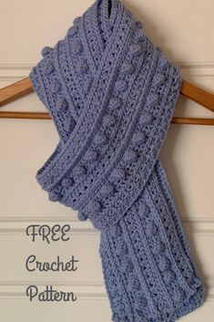 a blue knitted scarf hanging on a wooden hanger with the text free crochet pattern