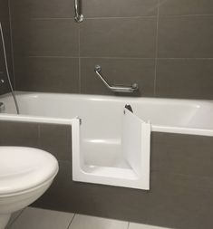 a white toilet sitting next to a bath tub in a bathroom under a faucet