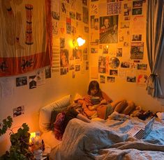 a woman sitting on top of a bed in a bedroom next to a wall covered with pictures