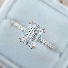 an emerald cut diamond ring with diamonds around it