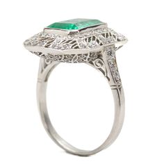 The Daphne ring was handmade in platinum and centers one natural Colombian emerald that weighs 2.70ctw which is surrounded by 76 old mine cut diamonds of H color and VS1 clarity that weigh 0.70ctw. This ring is currently size 7 and can be sized. Total weight: 6.3 grams/ 4dwt Ring measurement: 19mm by 16mm by 7mm Silver Emerald Cut Ring With Pave Setting, Art Deco Platinum Emerald Cut Emerald Ring, Octagon Emerald Platinum Ring For Wedding, Octagon Emerald Ring In Platinum For Wedding, Octagon Emerald Ring In Platinum, Fine Jewelry, Octagon Platinum Emerald Ring, Silver Octagon Emerald Ring With Halo Setting, Octagon Emerald Ring In Platinum, Art Deco Emerald Ring With Platinum