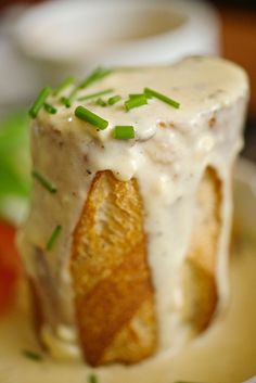 a piece of bread covered in white sauce and chives on top of a plate