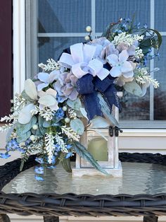 a vase filled with blue flowers sitting on top of a table next to a window