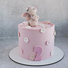 a pink birthday cake with an elephant on top