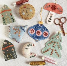 various ornaments are laid out on a white sheet with scissors and thread spools