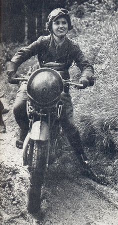 a man riding on the back of a motorcycle down a dirt road