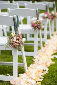 the aisle is lined with white chairs and decorated with pink, peach and green flowers