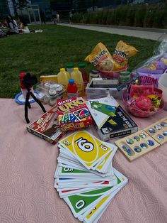 the table is covered with cards, snacks and condiments for an outdoor party