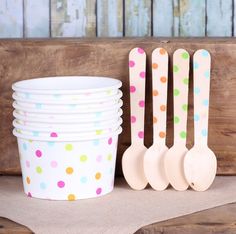 wooden spoons and cups are lined up against a wood board with polka dots on them