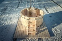 a wooden hot tub sitting on top of snow covered ground