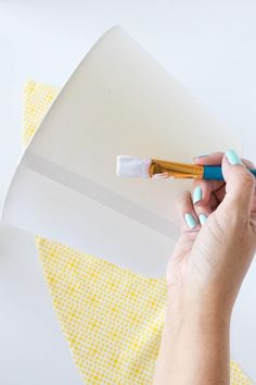 a woman is holding a pen and drawing on a piece of white paper with yellow polka dots