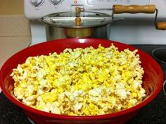 a red bowl filled with popcorn sitting on top of a stove