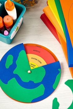 there is a clock made out of paper on the table next to markers and pencils