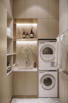 a washer and dryer in a room with beige cabinets, marble counter tops