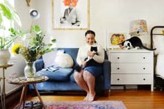 a person sitting on a couch in a living room with a cat laying on the floor