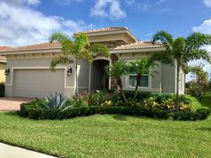 a house with palm trees in front of it and landscaping on the lawn behind it