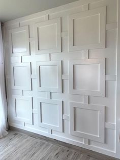 an empty room with white paneled walls and wood flooring on the side wall