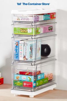 the container store has three clear bins with different types of books in them on top of a wooden table