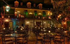 an outdoor dining area with tables and chairs lit up at night in front of a building