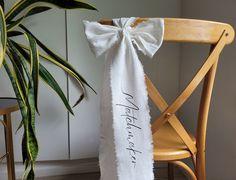 a chair with a white ribbon tied to it and a potted plant in the background