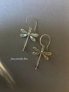 Beautiful silver dragonfly earrings with amethyst beads. Very detailed silver dragonflies are on handmade stainless steel ear hooks. Total earring length is just under 2 inches. *Silver plated brass dragonflies *Stainless steel ear hooks *Faceted amethyst beads *Handmade with love <3 Like Jmesjewelrybox on Facebook for updates on new jewelry, upcoming sales and giveaways! Plus Facebook fans save 5% :D Find the coupon code on Jmesjewelrybox's cover photo https://www.facebook.com/Jmesjewelrybox Elegant Sterling Silver Dragonfly Earrings, Silver Sterling Dragonfly Earrings, Sterling Silver Dragonfly Earrings, Elegant Adjustable Dragonfly Jewelry, Dainty Nickel-free Purple Earrings, Dainty Purple Nickel-free Earrings, Dainty Sterling Silver Dragonfly Jewelry, Nickel-free Adjustable Dragonfly Jewelry, Elegant Dragonfly Jewelry With Ear Wire