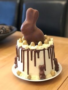 a chocolate bunny on top of a cake with white frosting and nuts around it