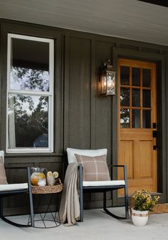 two chairs sitting on the front porch of a house next to a basket full of fruit