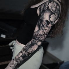 a woman's arm with a skull and flowers tattoo on the left side of her arm