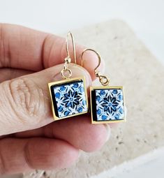 These Portuguese tile earrings are made with small wood cutouts, Portuguese typical tiles, gold steel settings and the design is transferred to it. These blue and gold tiles patterns are very common to be found in the city of Porto, north of Portugal. ∙ DESCRIPTION & MATERIALS ∙ * Materials: FSC certified wood, Portuguese tile pattern and high quality metal findings. * Ear Wires Finish: Plated, steel or sterling silver * Featuring a 1.2 cm x 1.2 cm Square mini tile, or 1/2'' x 1/2'' inches * Handmade in France * Anti allergic * Resistant & Durable * Handmade finish and detail * Each "tile" piece is sealed and coated with water based and nontoxic glaze, just like in ceramic pieces * Nickel and lead-free earring ear wires * Follow of the European norms for metal use safety * Ethical producti Blue White Tile, Gold Tiles, Tile Earrings, Spouse Gifts, Gold Tile, Portuguese Tile, Small Tiles, Ceramic Pieces, Tile Pattern