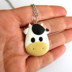 a hand holding a small cow shaped pendant