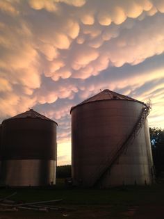 the sky is filled with clouds over two silos